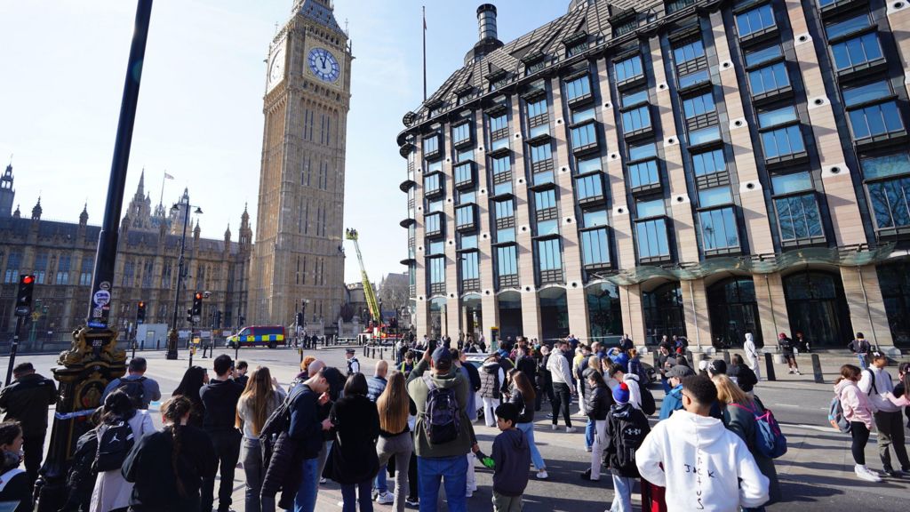 People watch a man with a Palestine flag after he climbed up Elizabeth Tower.