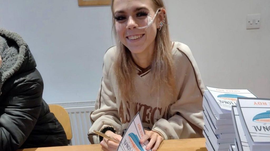 A girl signing copies of a book