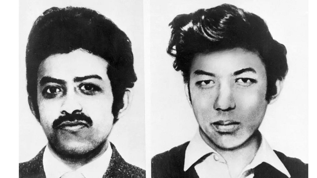 Custody photos of Arthur and Nizam Hosein side by side, in black and white. They both wear white shirts and dark jackets. They have 1960s fashion hairstyles and Arthur has a moustache while Nizam is clean shaven. 