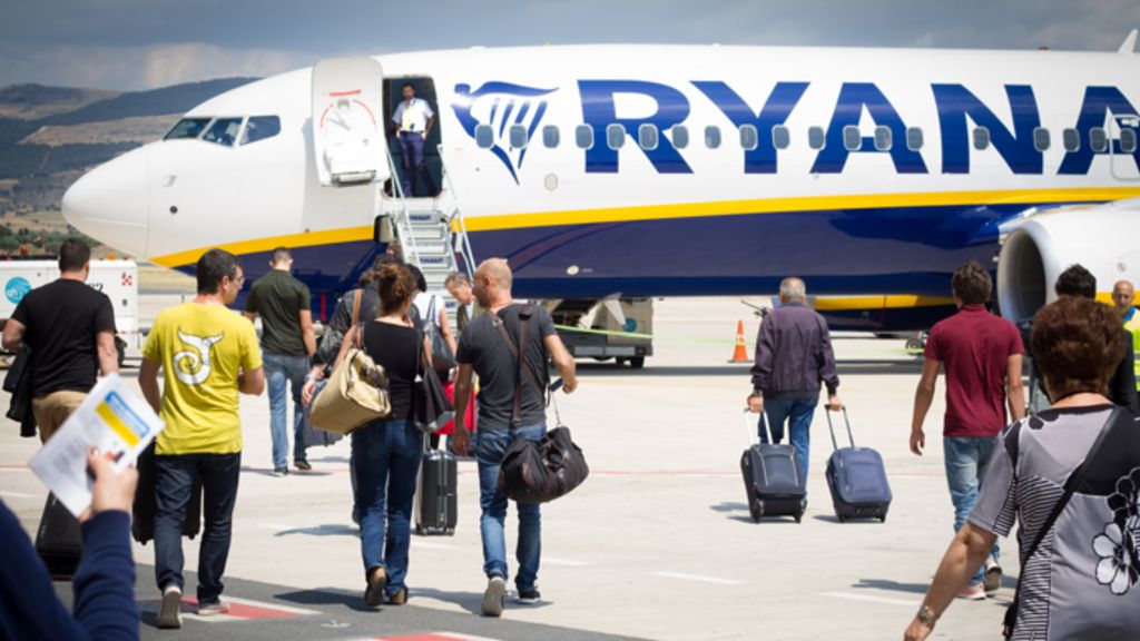 Passengers head towards a Ryanair plane on a runway