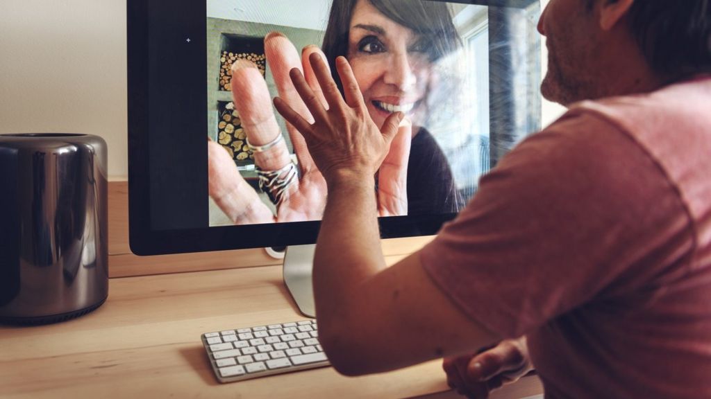 Man and woman hold hands via video conference