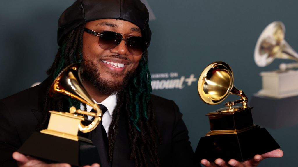 Leon Thomas holding two Grammy Awards