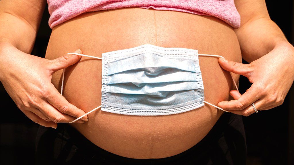 Face mask spread over a pregnant woman's stomach