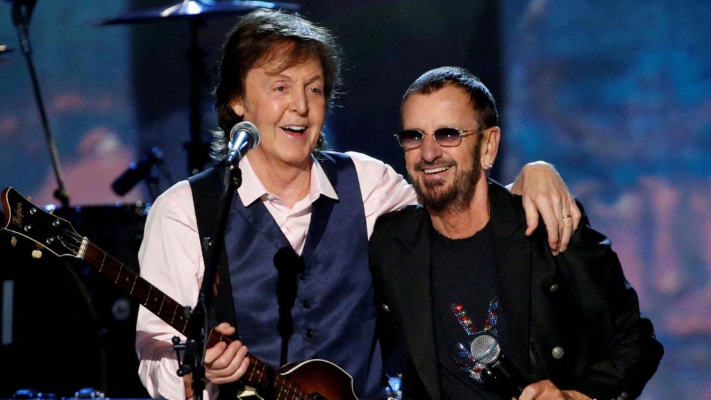 Paul McCartney holding his bass in one hand with his other hand resting on Ringo Starr's shoulder, during the taping of The Night That Changed America: A Grammy Salute To The Beatles, in 2014