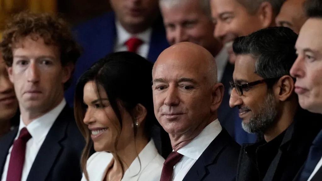 Mark Zuckerberg and Jeff Bezos wearing similar navy suits, with white dress shirts and dark red ties at the second inauguration of Donald Trump. Sundar Pichai and Elon Musk are next to them, both dressed in black.
