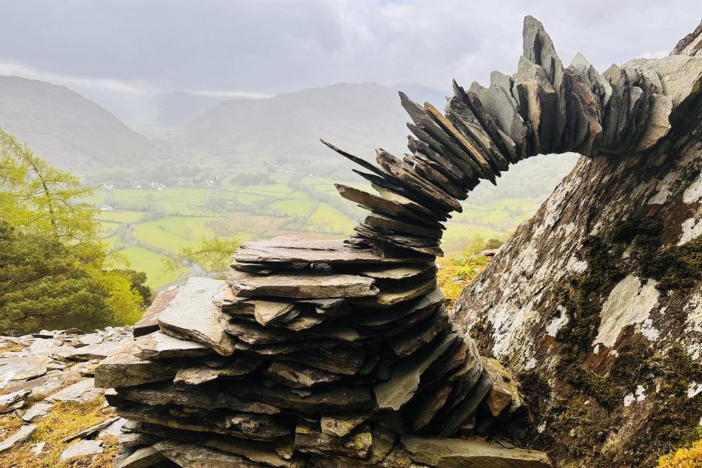 Flat slates piled on top of each other in a curve against a rock face