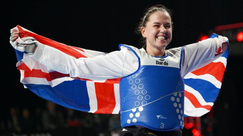 Beth Munro holds the Union flag behind her back in celebration