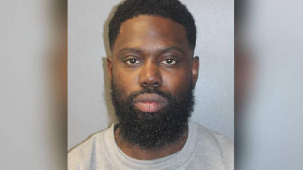 Justin Clarke-Samuel's police mugshot. He wears a grey top and is looking at the camera.