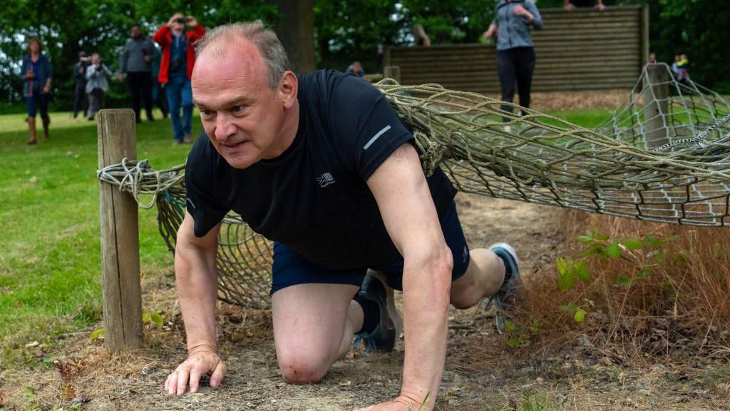 Ed Davey crawls through obstacle course