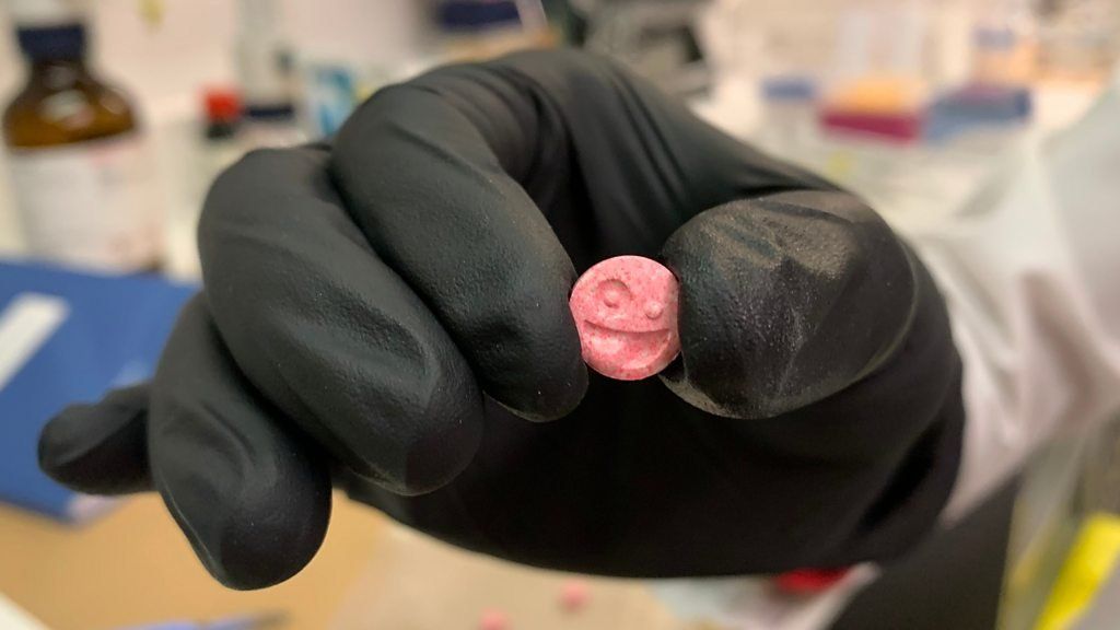 A pill being held by a hand