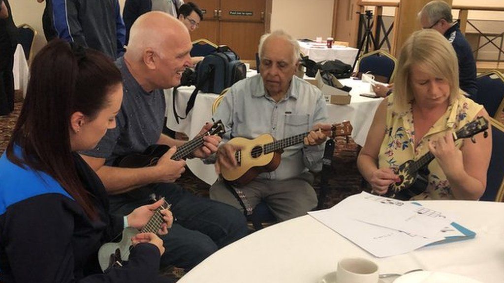 Tony Grimwood (left) teaches participants how to play the ukulele at Wigan Athletic's Extra Time Hub