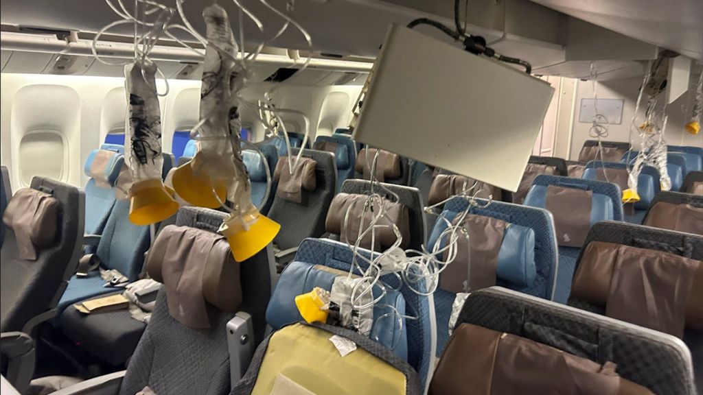 The plane seats with emergency oxygen masks down and people's belongings strewn about