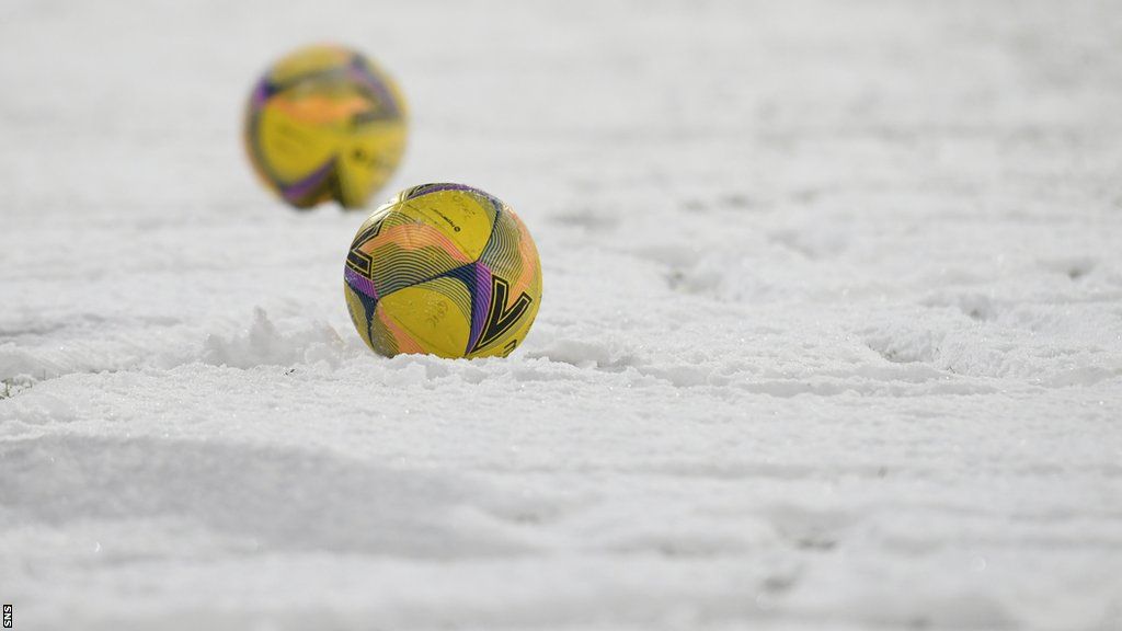 Two footballs sit on snow