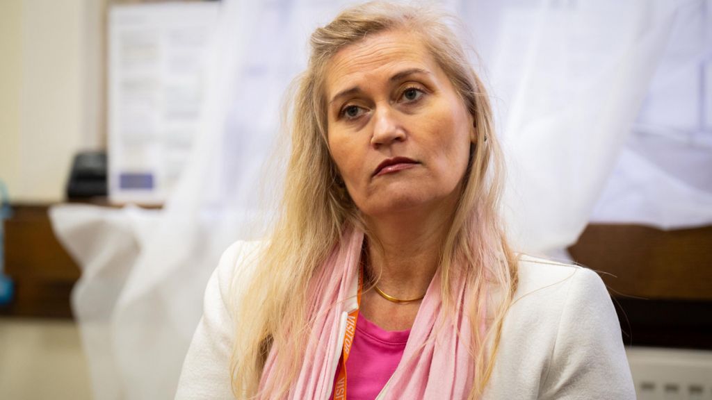 Katalin Kaszas in a white suit and pink top. She has blond hair