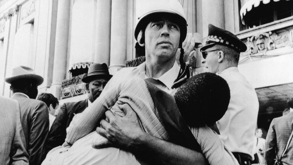 Chicago police officer carries a young anti-war protestor who fainted during the protests