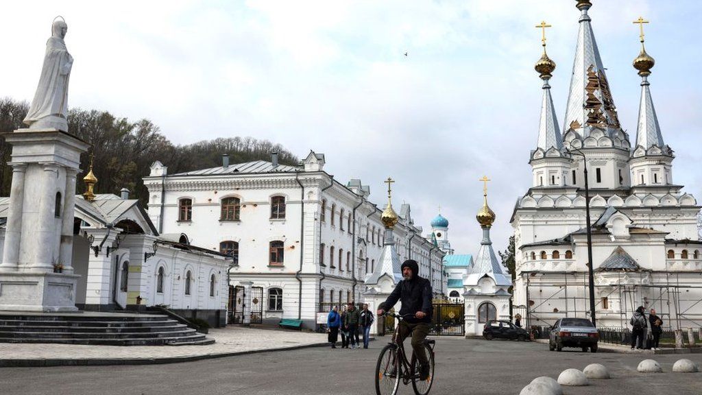 A man ride his bicycle near the damaged Sviatohirsk Cave Monastery, an Orthodox Christian monastery on the bank of the Seversky Donets River near the town of Sviatohirsk (Svyatohirsk)