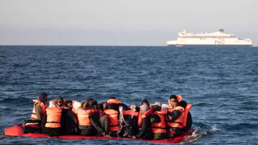 Refugees/asylum seekers in life jackets on boat in the Channel, P&O ferry in the background
