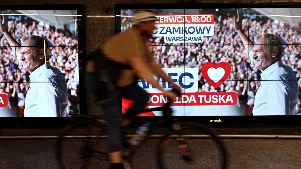 A man rides a bicycle through an underground passage past advertising screens announcing the upcoming rally of Poland's Prime Minister Donald Tusk, scheduled for June 4, in Warsaw, Poland on May 28, 2024