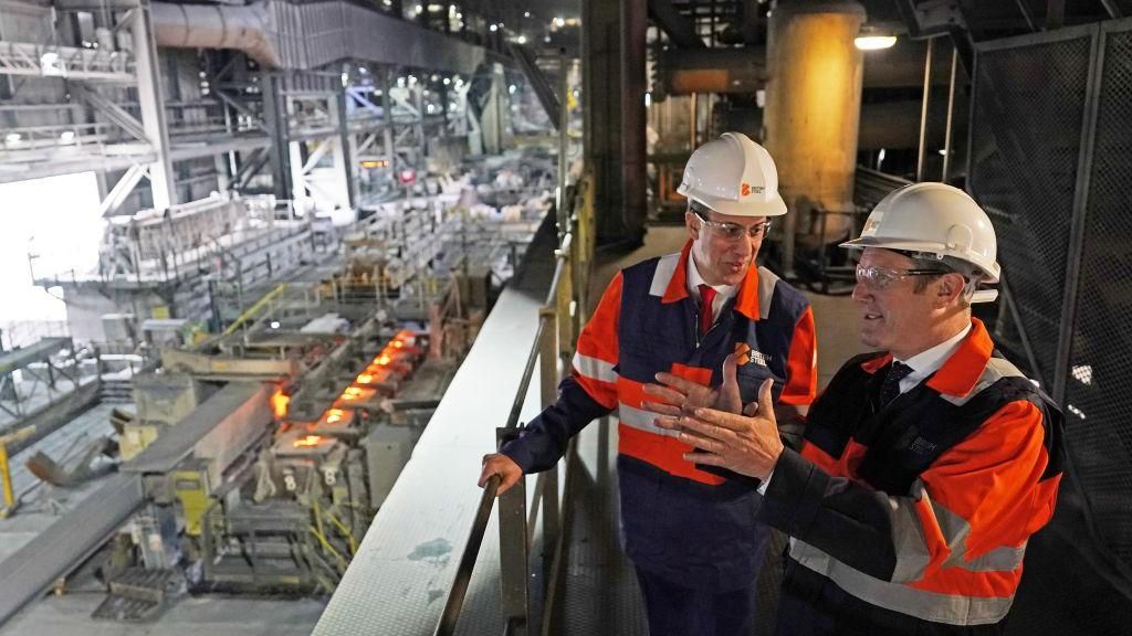 Ed Miliband and Sir Keir Starmer in a steel plant in Scunthorpe, wearing high-vis jackets and hard hats 