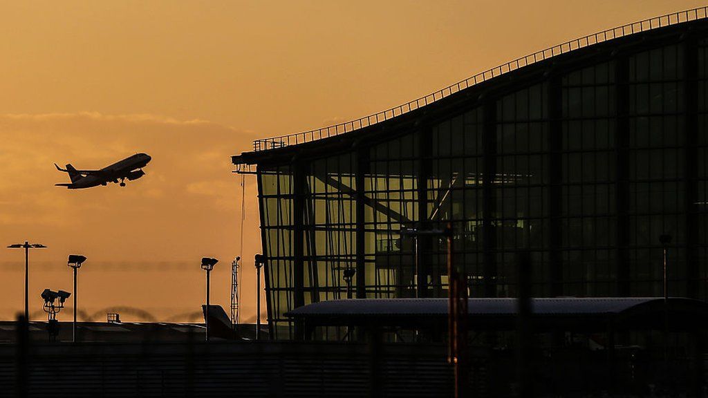 A passenger aircraft takes off alongside Terminal 5 during sunrise at London Heathrow Airport in west London on 17 October 2016.