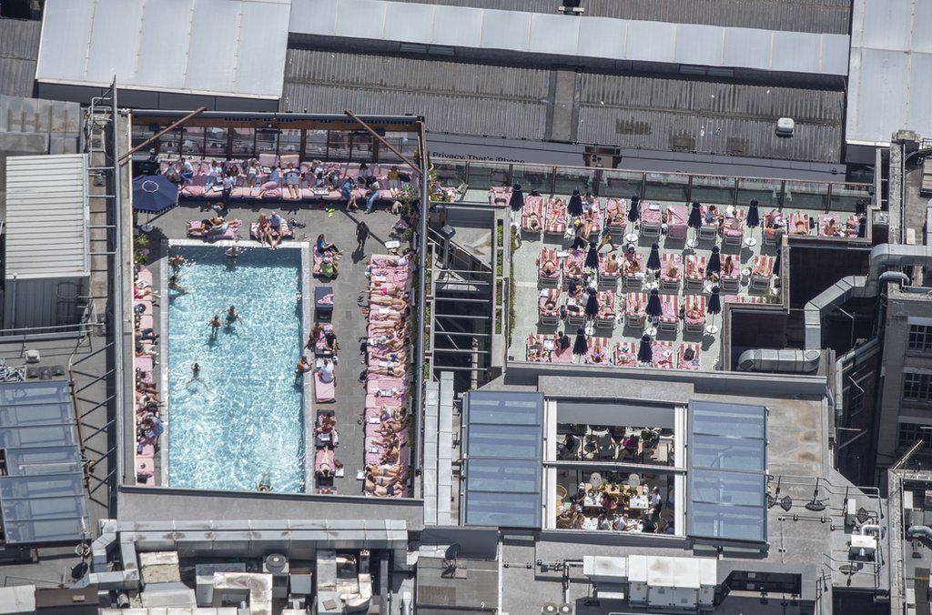 PEOPLE SUNBATHING AND SWIMMING AT THE ROOF TOP POOL AT SHOREDITCH HOUSE