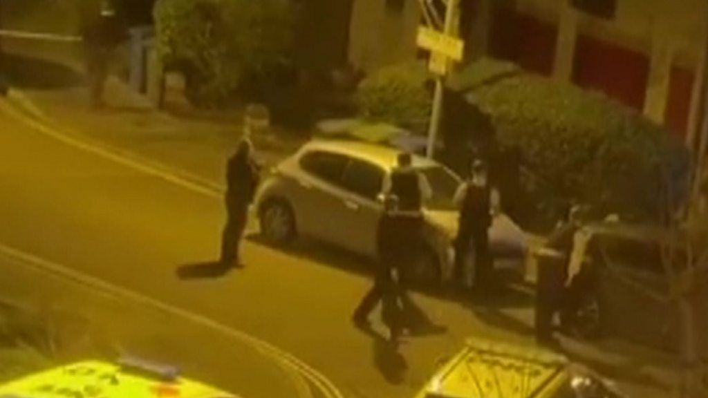 Armed police stand outside building at night