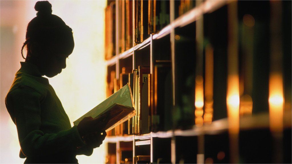 Девушка читает книгу в библиотеке
