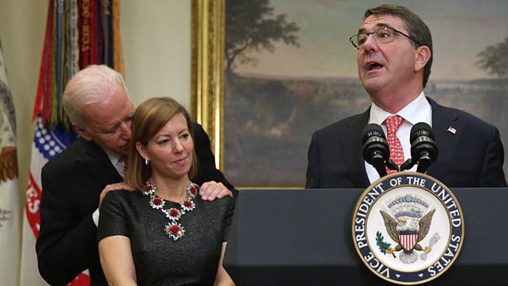 Joe Biden with his hands on the shoulder of Stephanie Carter in 2015 while her husband, US Defense Secretary Ash Carter gives a speech