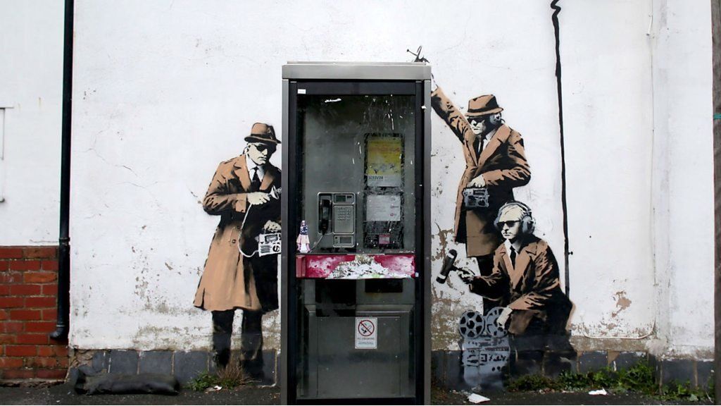 Spies listening to a conversation in a telephone box