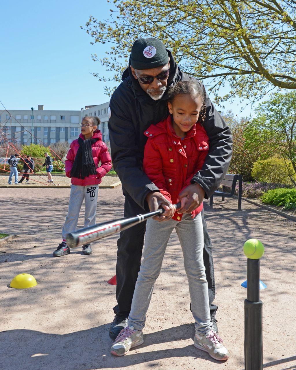 Melvin McNair showing a child how to play baseball in 2013