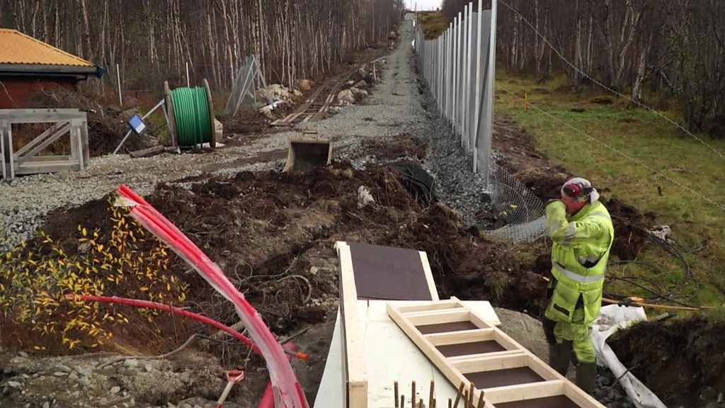 Worker building fence on Norway's border