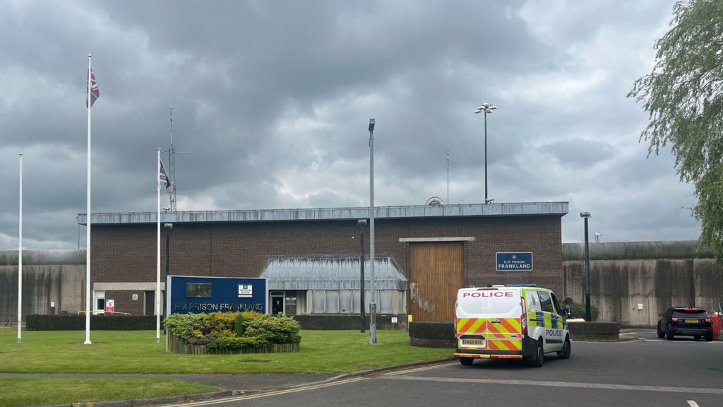 A landscape view of a HMP Frankland building. A police van is seen in the foreground - a sign reading H.M. Prison FRANKLAND is just visible on the building.

