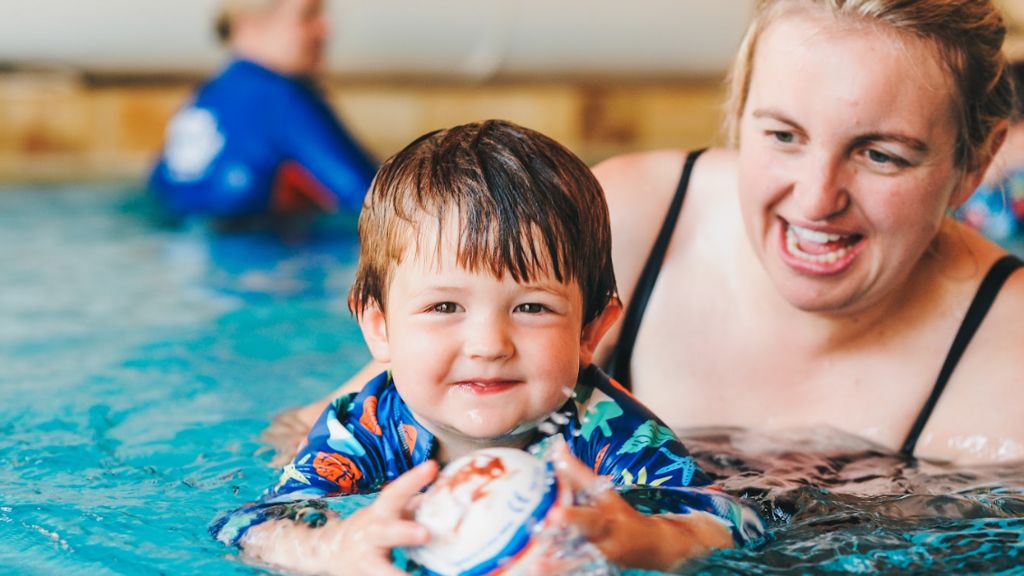 A mother in the swimming pool holding a child