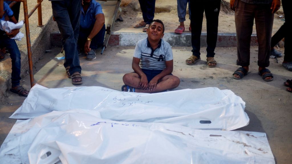 A boy reacts next to the bodies of Palestinians, following an Israeli strike, amid the Israel-Hamas conflict, at Nasser hospital in Khan Younis