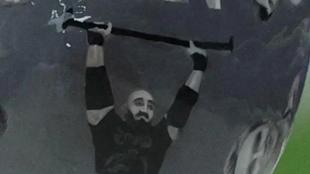 Close up of the helmet featuring an image of Pavlo Ishchenko powerlifting. He is bald with a beard and moustache.