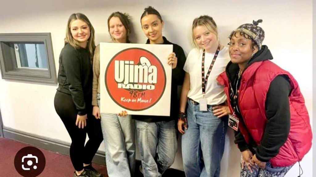 Five people pictured next to a square shaped canvas with the Ujima radio logo