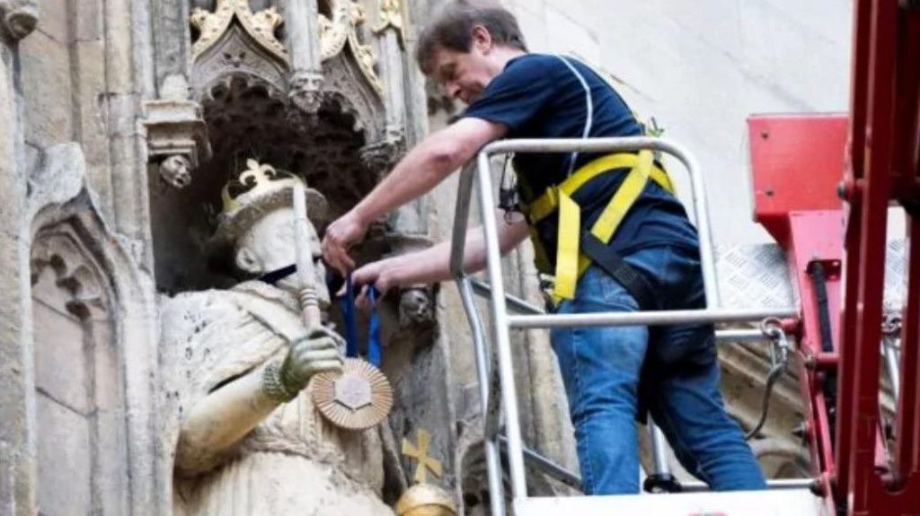 Man hanging medal on statue