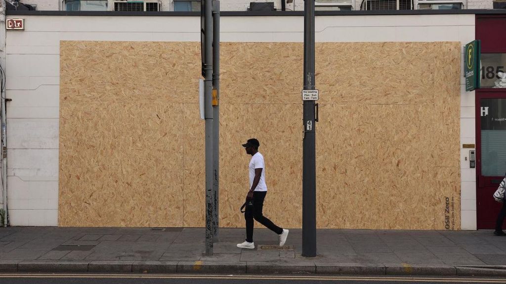 immigration Bureau in Waltham Forest with boards across the windows - a man walks past the front