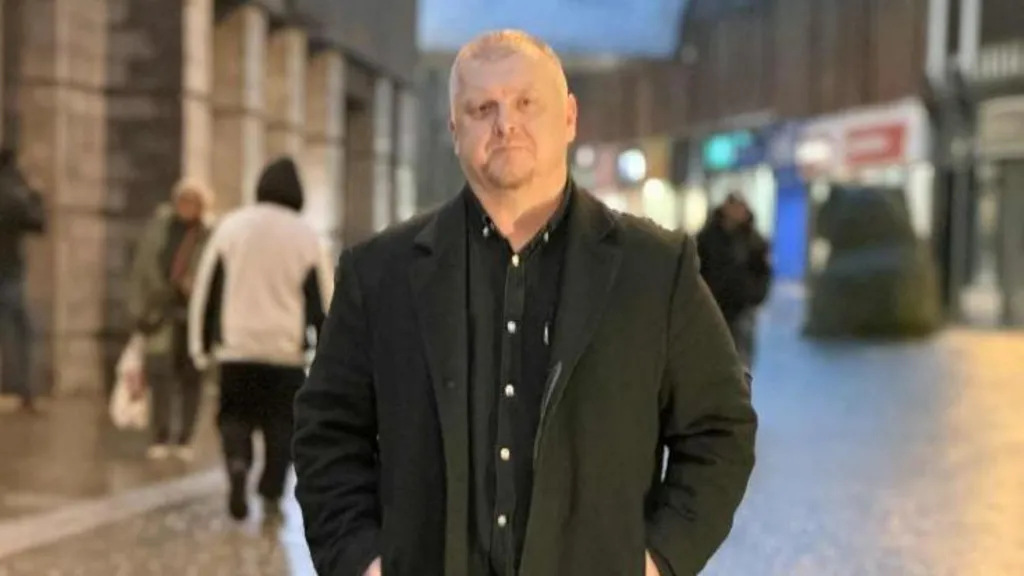 A man in a dark jacket stood on a street