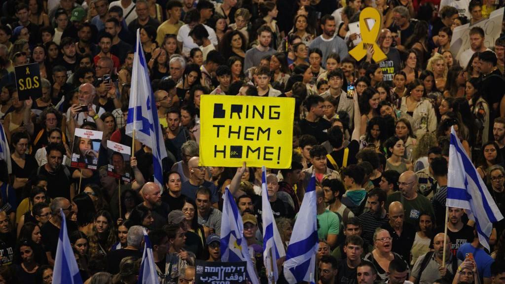 A crowd of Israeli protestors in Tel Aviv, with one large yellow sign reading 'Bring them home!'