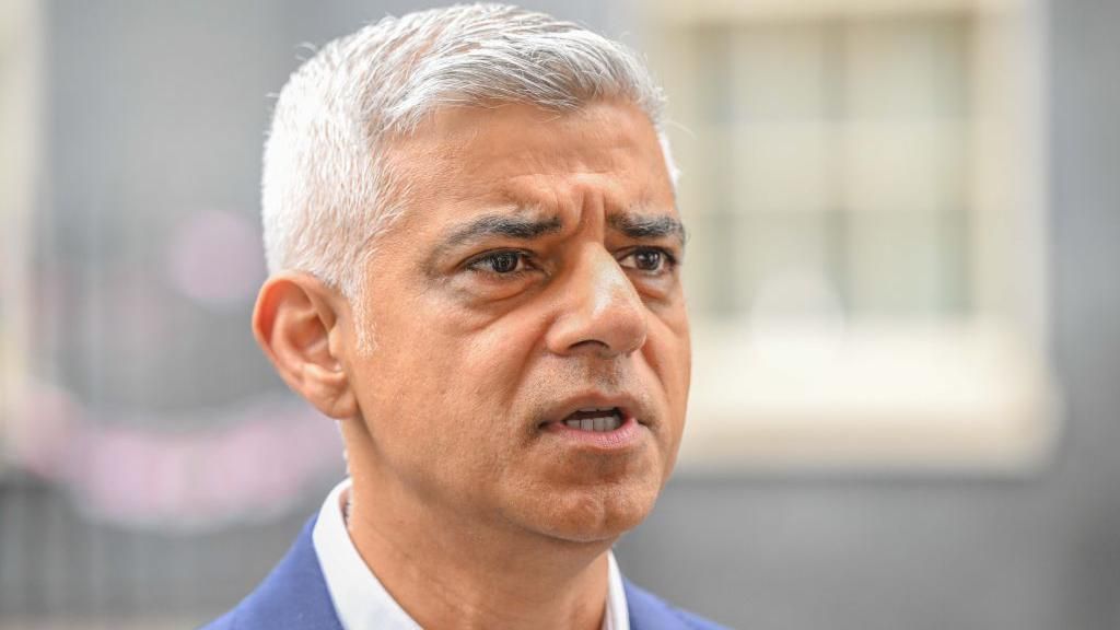 Sadiq Khan looking towards the right of the picture, he has white hair and has a serious expression.