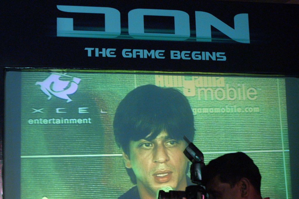 A member of the media stands in front of a big screen as he photographs Indian filmstar Shahrukh Khan at the launch of a mobile game based on his new film 'DON' in Mumbai, 27 October 2006.