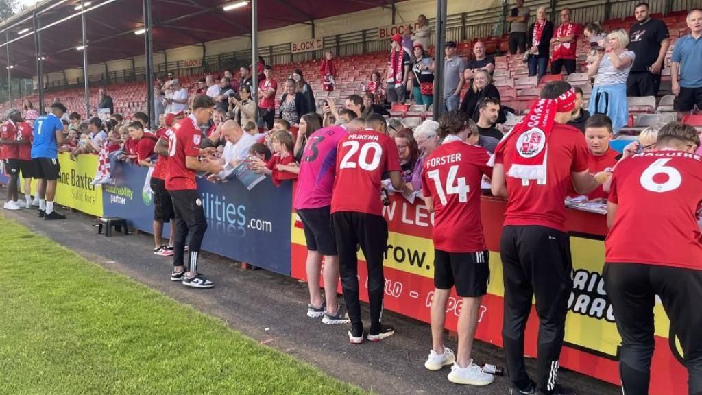 Crawley players sign autographs for fans