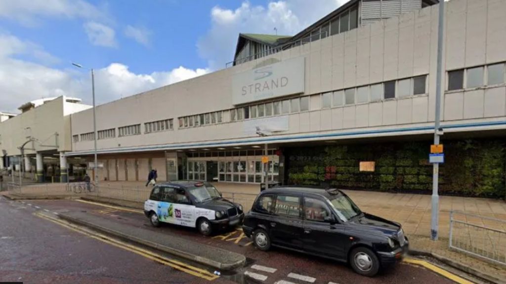 Two taxis wait outside The Strand shopping centre in Bootle