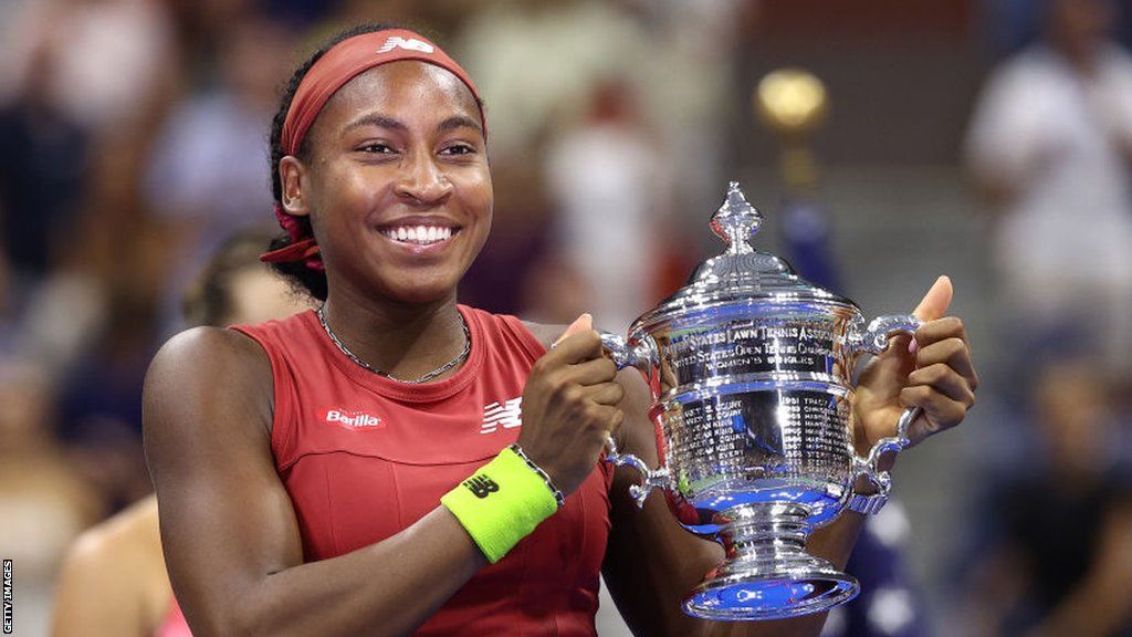 Coco Gauff smiles as she lifts the US Open trophy