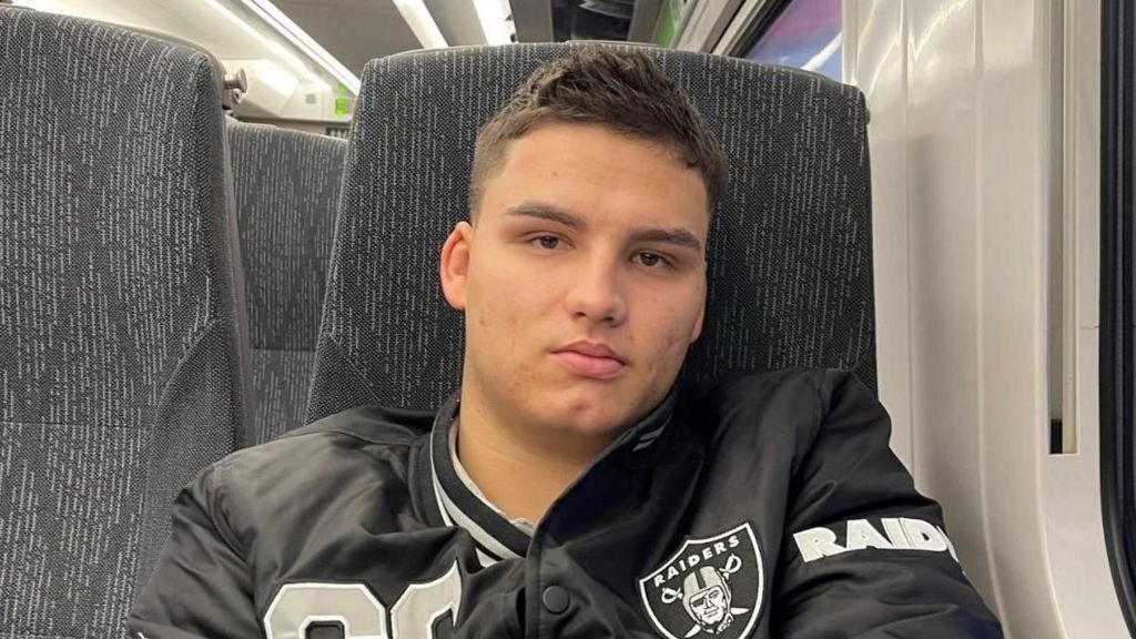 Narcis Titianu, pictured on a train. He is wearing a sports jacket, has short dark hair and is smiling at the camera. 