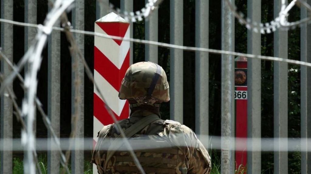 A soldier stands guard near the fence on the Belarusian-Polish border near Bialowieza, Poland, 4 June 2024.
