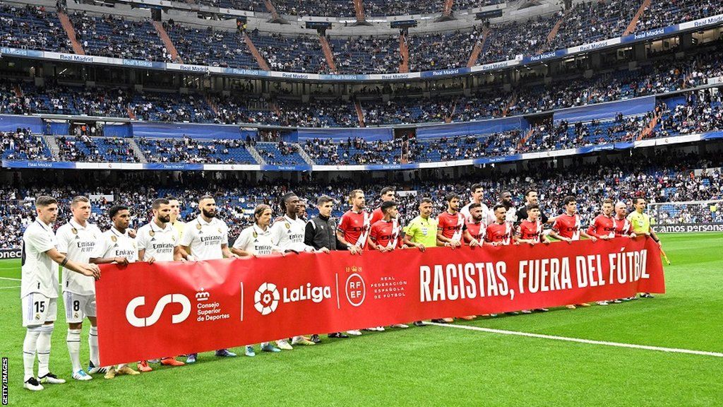 Real Madrid and Rayo Vallecano players hold a banner saying "racists out of football" in support of Vinicius Jr before Wednesday's La Liga match at the Bernabeu
