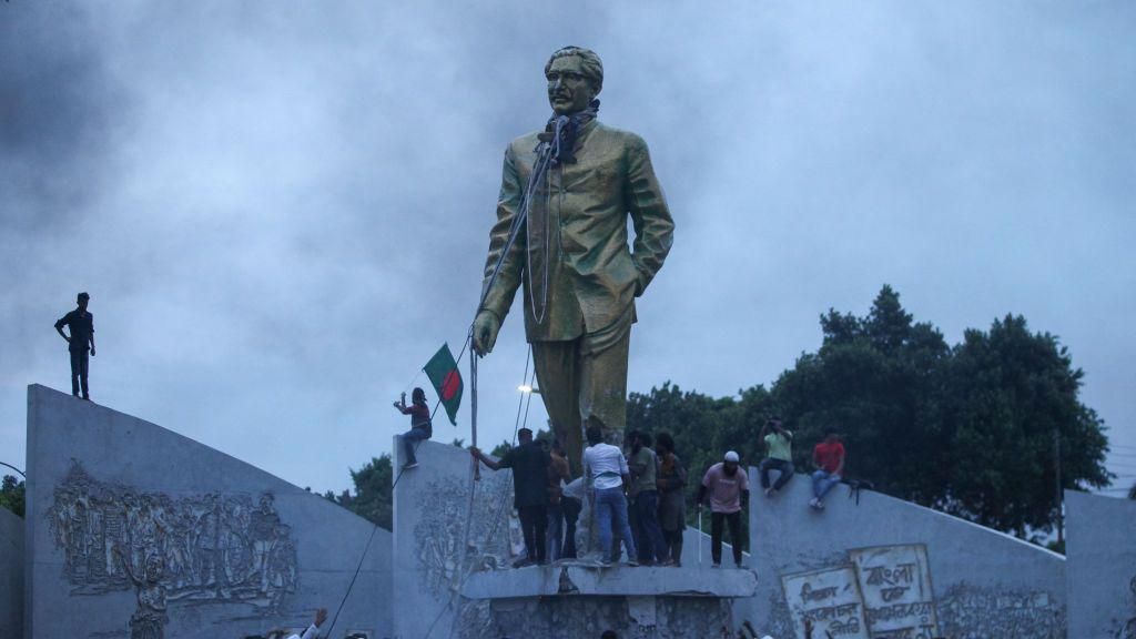 Demonstrators attempting to tear down a statue of Ms Hasina's father, Sheikh Mujibur Rahman