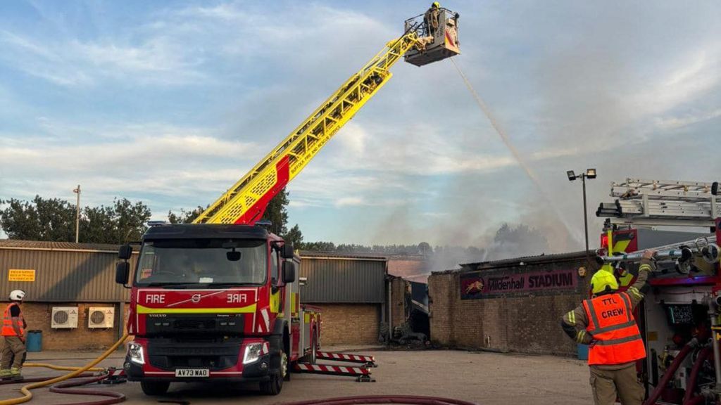 A firefighter on an aerial ladder platform hosing down the fire